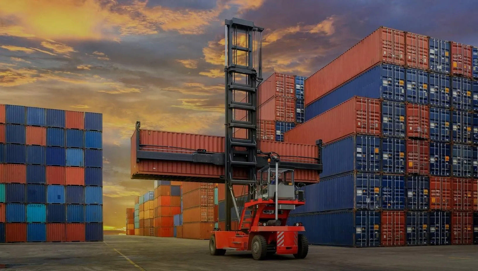 Alquiler de contenedores marítimos Pilas de contenedores en un depósito y carretilla portacontenedores: alquiler de contenedores marítimos
