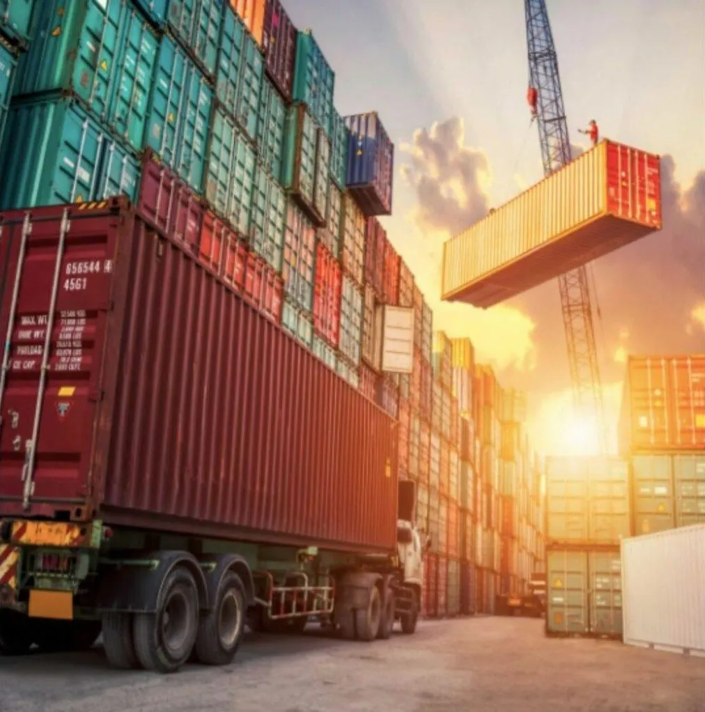 Traslado de contenedores ya instalados Camión con contenedor rojo y grúa izando otro contenedor en una terminal: traslado de contenedores